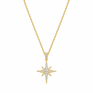 A gold chain necklace with a starburst pendant, displayed on a textured black leather surface.