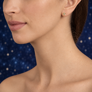 Luna gold star earrings model image with a blurred star-filled night sky
