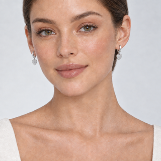 Model wearing Mae silver huggie hoop earrings with heart charms