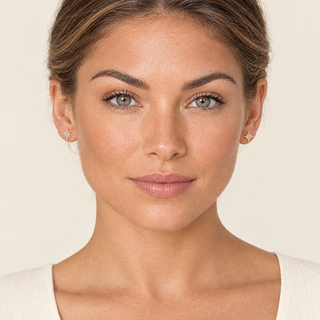 North Star gold earrings on a model in a cream studio setting